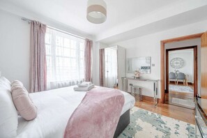 A bedroom with a bed, a desk, a mirror, and a door leading to another room. - Fantastic 1 Bedroom Apartment Just Off Marble Arch (London)