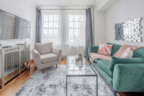 A living room with a sofa, armchair, coffee table, and a TV on the wall. - Fantastic 1 Bedroom Apartment Just Off Marble Arch (London)