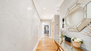 A hallway with a wooden floor, a glass table, and a wall-mounted phone. - Beautiful 2 Bedroom off Marble Arch (London)