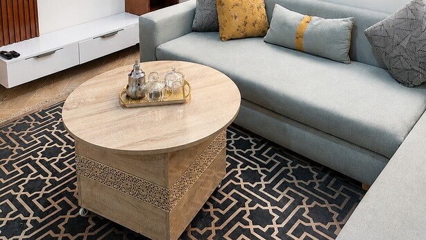 Una sala de estar moderna con sofá, mesa de centro, televisor y estantería.