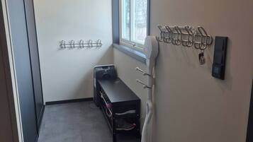 A narrow hallway with a bench, coat hooks, and a window.