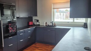 Una cocina moderna con armarios oscuros, piso de madera y ventana que deja entrar luz natural.