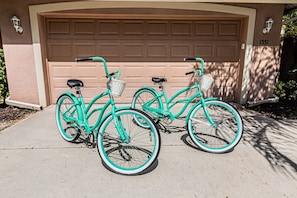 Een turquoise fiets met een mandje en een zitting, geparkeerd voor een garage.
