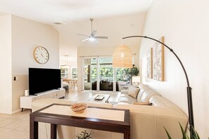 A living room with a television, sofa, coffee table, and a dining area with chairs and a table. - Newly Listed - Briarwood Pool/Spa home w/outdoor 65" smart TV & conversational seating area (Naples)