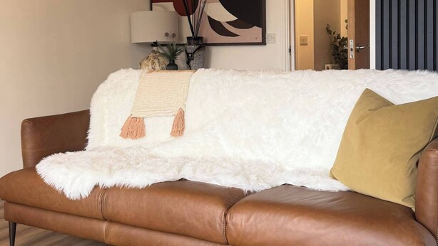 A brown leather sofa with a white fluffy throw blanket and a mustard-colored pillow. - Executive 2-bedroom Corporate Space In West Yorkshire, United Kingdom (Leeds)