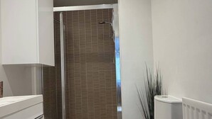 A modern bathroom with a shower, toilet, and a white cabinet. - Executive 2-bedroom Corporate Space In West Yorkshire, United Kingdom (Leeds)