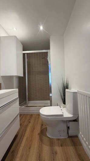 Ein modernes Badezimmer mit Dusche, Toilette und einem weißen Schrank.