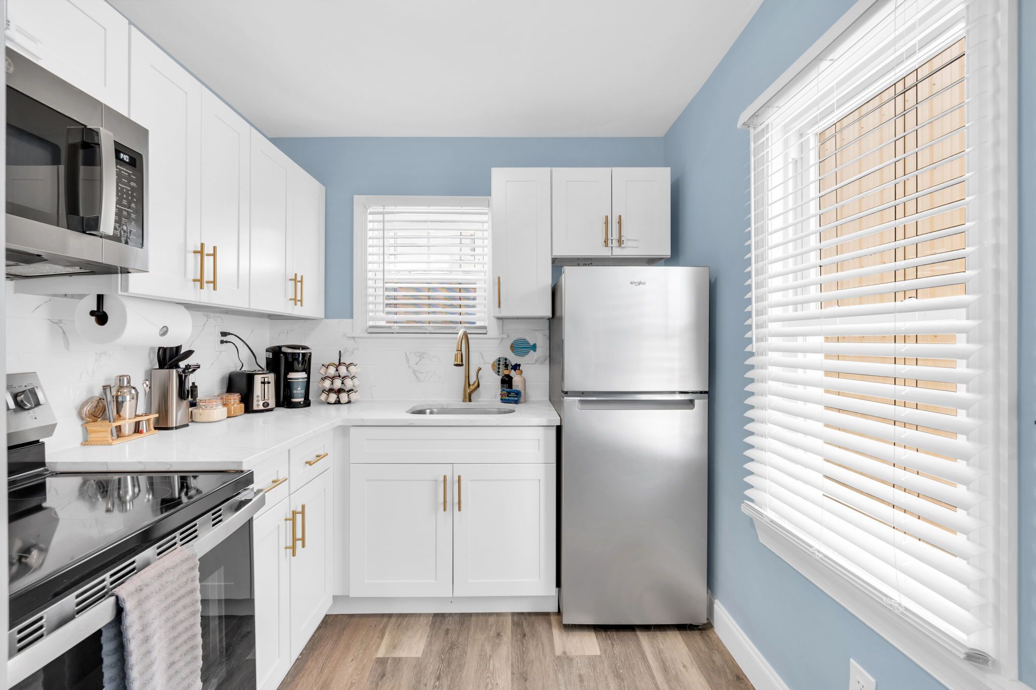 A modern kitchen with white cabinets, a stainless steel refrigerator, and a microwave.
