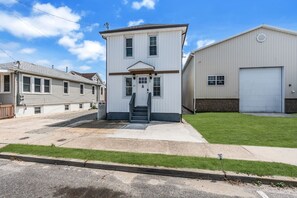 A two-story building with a front entrance, a garage, and a well-maintained lawn. - King Bed | Half Block to Beach | Prof Managed (Seaside Heights)