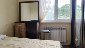 A bedroom with a bed, a dresser, a mirror, a radiator, and a window with curtains. - Max House . botanical garden full room (Yerevan)