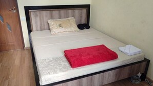 A single bed with a wooden headboard, a red blanket, and a pillow with a design. - Max House . botanical garden full room (Yerevan)