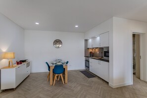 A compact kitchen with white cabinets, a dining area with a table and chairs, and a wall clock. - GuestReady-Charming Retreat in Ribeira Grande (Ribeira Grande)