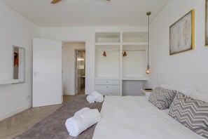 A bedroom with a bed, a bedside table, a wardrobe, and a door leading to a bathroom. - GuestReady-Charming Retreat in Ribeira Grande (Ribeira Grande)