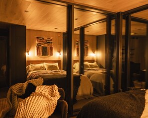 Una habitación con dos camas, un espejo grande y techo de madera.