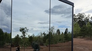 Un bâtiment moderne à la façade de verre qui reflète le paysage environnant.