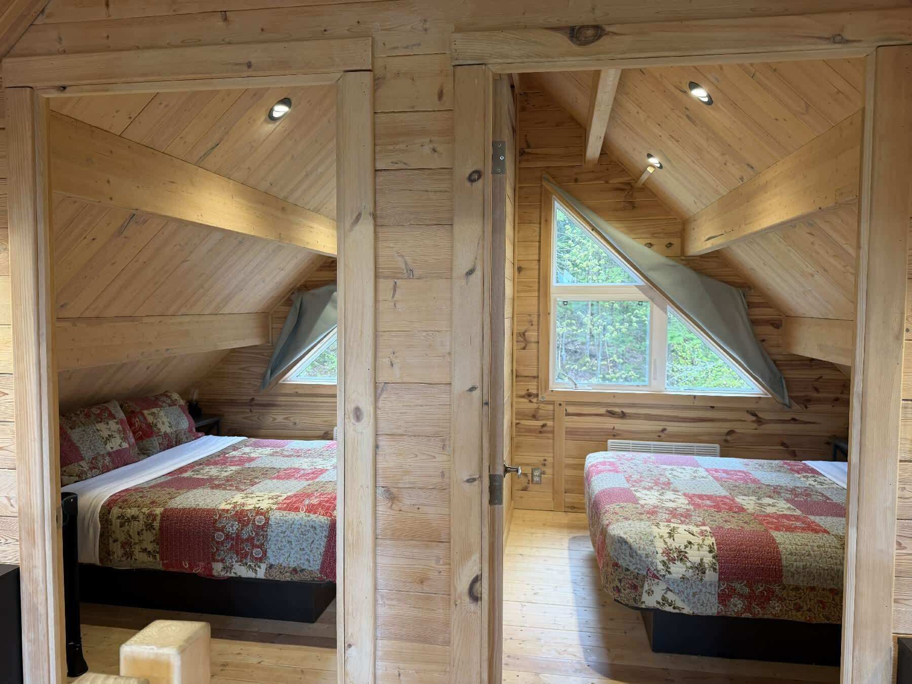 Une cabane en bois avec deux chambres, chacune comprenant un lit et une fenêtre.