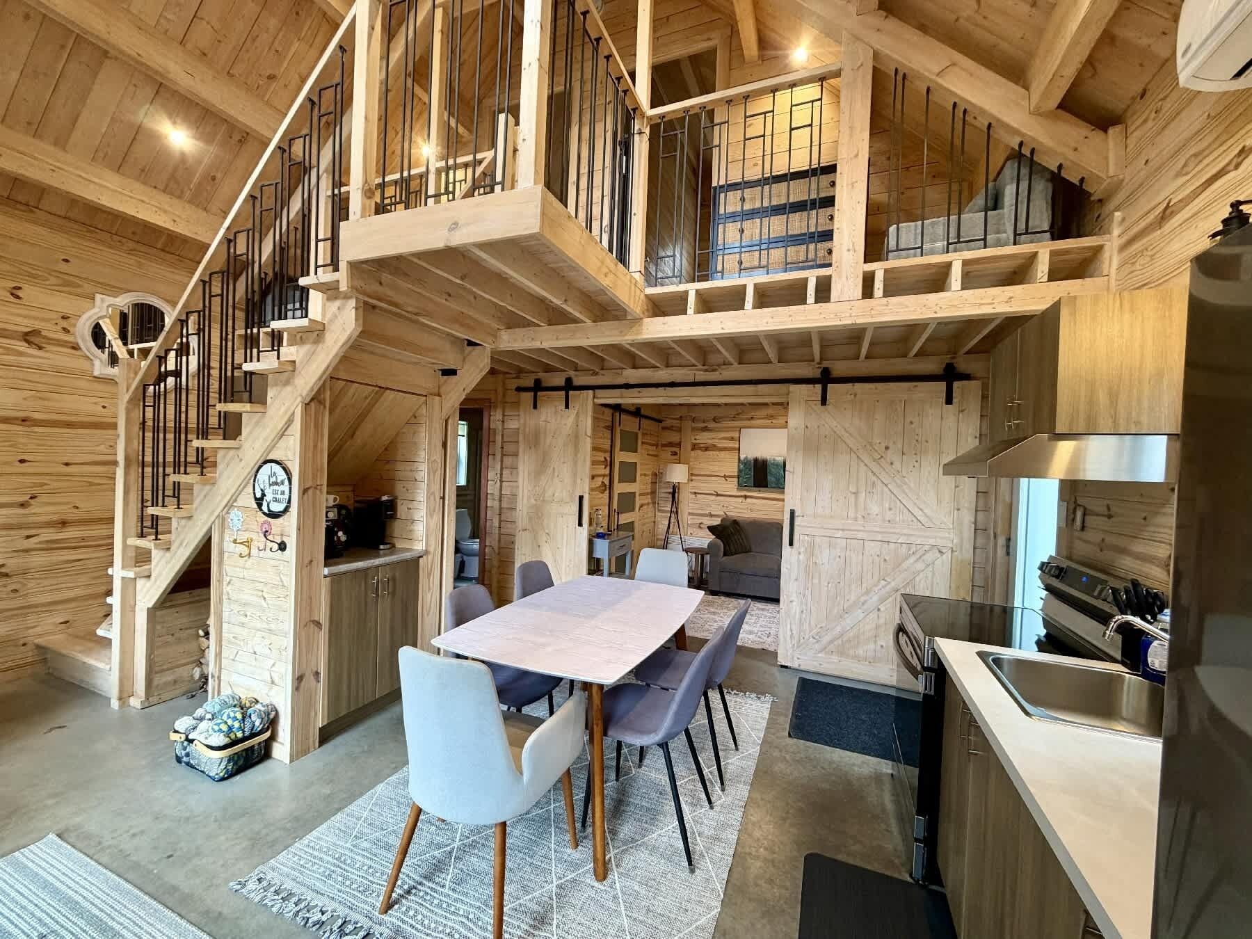 A wooden interior with a dining area, kitchen, and a staircase.