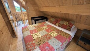 A wooden interior with a bed, a window, and a staircase.