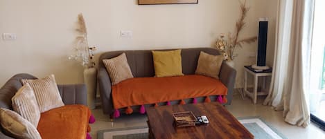 Una sala de estar con sofá, sillón, mesa de centro y una araña.