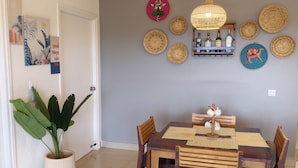A dining area with a wooden table and chairs, a hanging light fixture, and decorative wall hangings. - The Grove - Kudrat's Nilaya (Sea view apartment in Palolem) (Canacona)