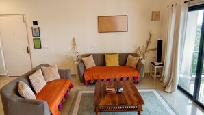 A living room with a sofa set, a coffee table, a chandelier, and a large window with curtains. - The Grove - Kudrat's Nilaya (Sea view apartment in Palolem) (Canacona)
