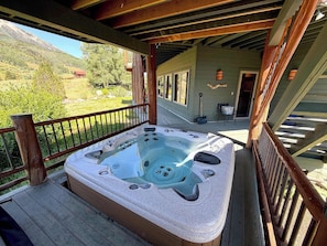 Ein Whirlpool auf einer Holzterrasse mit Blick auf eine gebirgige Landschaft.