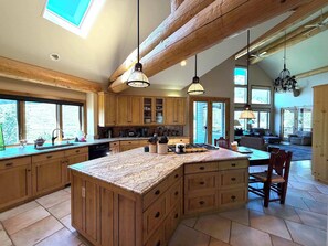 A spacious kitchen with wooden cabinets, a large island, and pendant lighting. - Slate River Retreat-Private hot tub & pet friendly (Crested Butte)