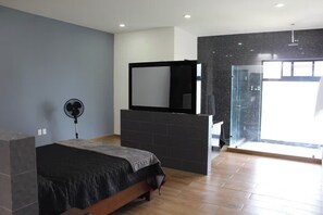 A bedroom with a bed, a fan, a mirror, and a shower area. - The Glass & Stones Oasis: An Urban Sanctuary (Temixco)