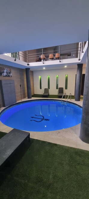 An indoor swimming pool with a modern design, a staircase, and a seating area with chairs. - The Glass & Stones Oasis: An Urban Sanctuary (Temixco)