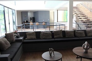 A modern living room with a sofa, a round table, and a staircase. - The Glass & Stones Oasis: An Urban Sanctuary (Temixco)