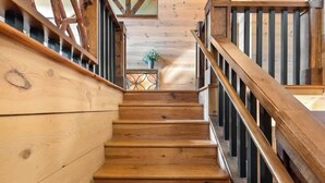 A wooden staircase with a railing, leading to a room with a wooden ceiling and a small table with a plant. - Mountain High - Hot Tub, Game Room and Views (Sapphire)