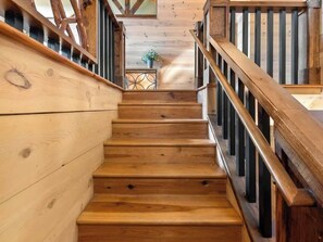 Eine Holztreppe mit Geländer, die zu einem Raum mit Holzboden und einem kleinen Tisch mit einer Pflanze führt.