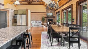 A spacious kitchen with granite countertops, wooden flooring, and a large dining area with a wooden table and chairs. - Mountain High - Hot Tub, Game Room and Views (Sapphire)