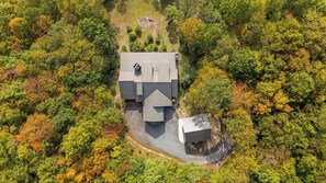 Eine Luftaufnahme eines Hauses, das von dichtem Wald umgeben ist.
