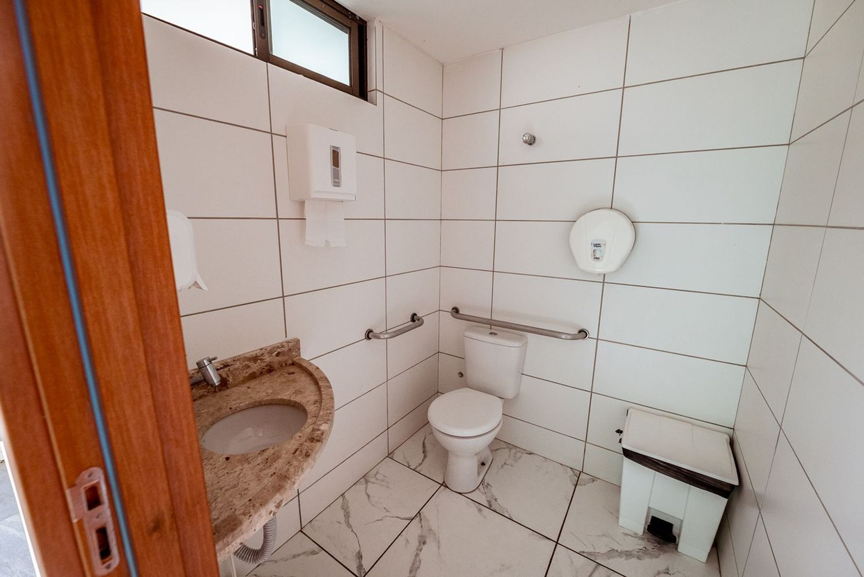 Casa de banho com sanita, lavatório e secador de mãos.
