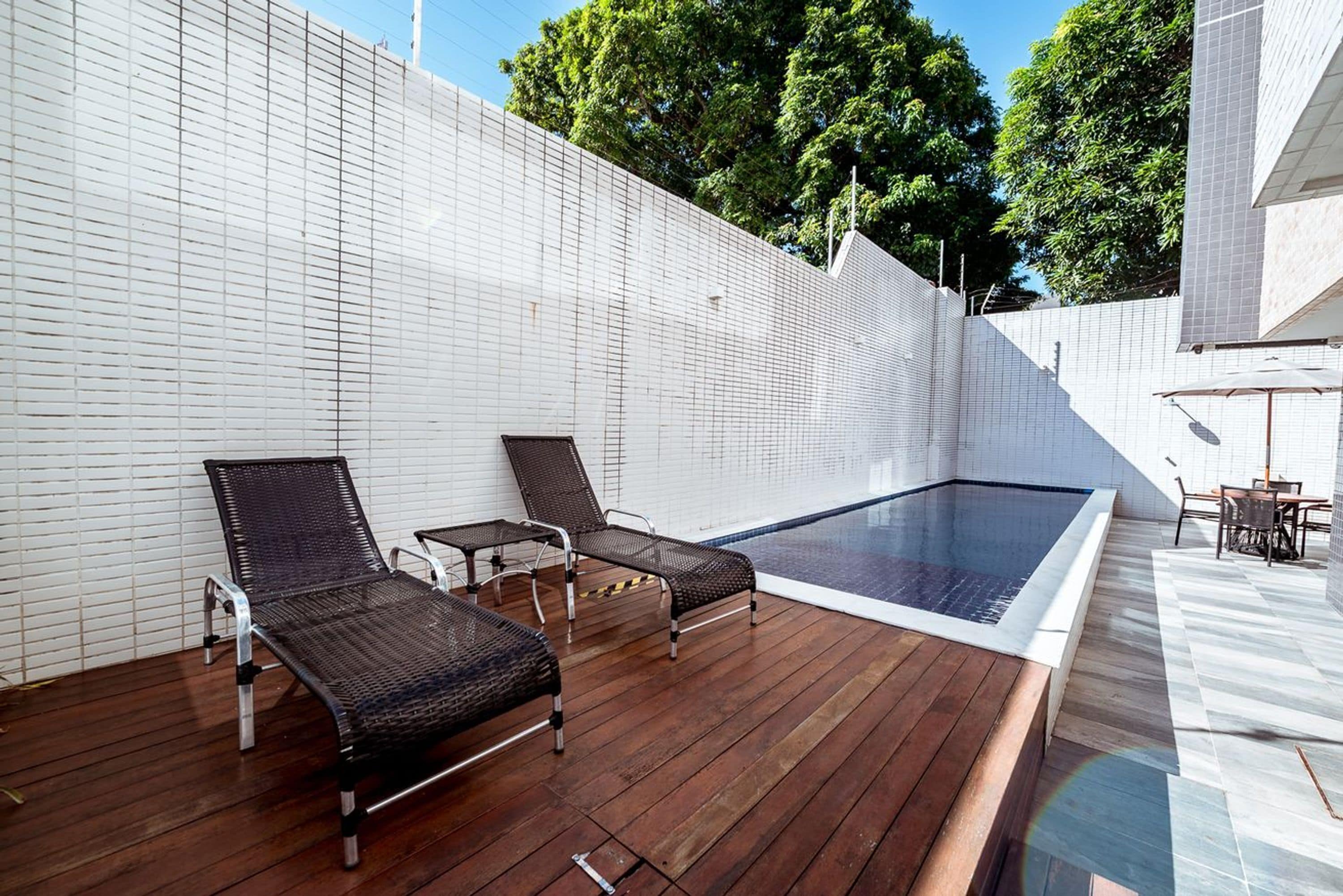 Ein Poolbereich auf dem Dach mit zwei Liegestühlen und einem kleinen Tisch.