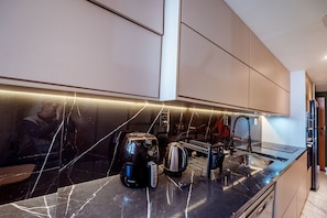 A modern kitchen with a black marble countertop, stainless steel appliances, and a sleek backsplash. - Apto com Piscina Academia e Churrasqueira (João Pessoa)