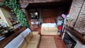 A cozy living room with a sofa, a coffee table, a fireplace, and a brick wall. - Casa Los Josuco, located in the heart of the Saja-Besaya Natural Park. (Collado de Cieza)
