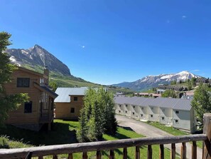 Ein Holzhaus mit Balkon, eine Reihe von Hütten und ein Berg im Hintergrund.