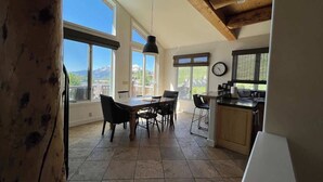 Cozinha espaçosa com área de jantar, grandes janelas e vista para as montanhas.