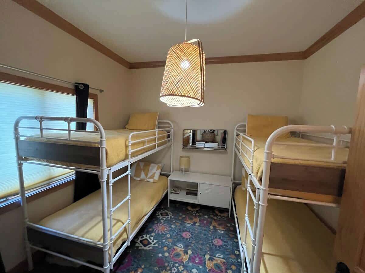 A bunk room with metal bunk beds, a small desk, a mirror, and a hanging light fixture.
