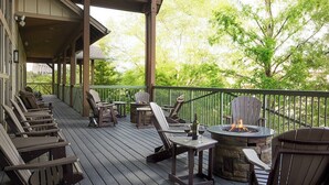 Un área de estar al aire libre techada con sillones Adirondack y un hogar a leña de piedra.