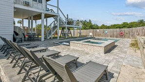 Um quintal com piscina, área de estar externa, deck de madeira e escadaria para uma área coberta.