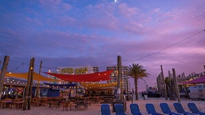 Restaurante à beira-mar com mesas ao ar livre e toldo.
