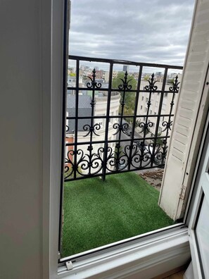 Een balkon met een metalen hekwerk en een klein stukje kunstgras.
