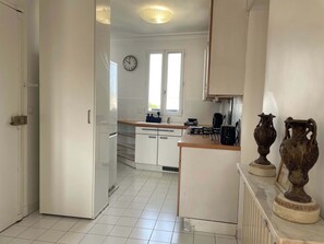 Eine Küche mit weißen Schränken, einer Uhr an der Wand und zwei Vasen auf der Arbeitsplatte.