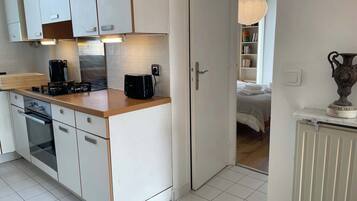 Une cuisine moderne avec des meubles blancs, un plan de travail, une machine à café et un grille-pain.