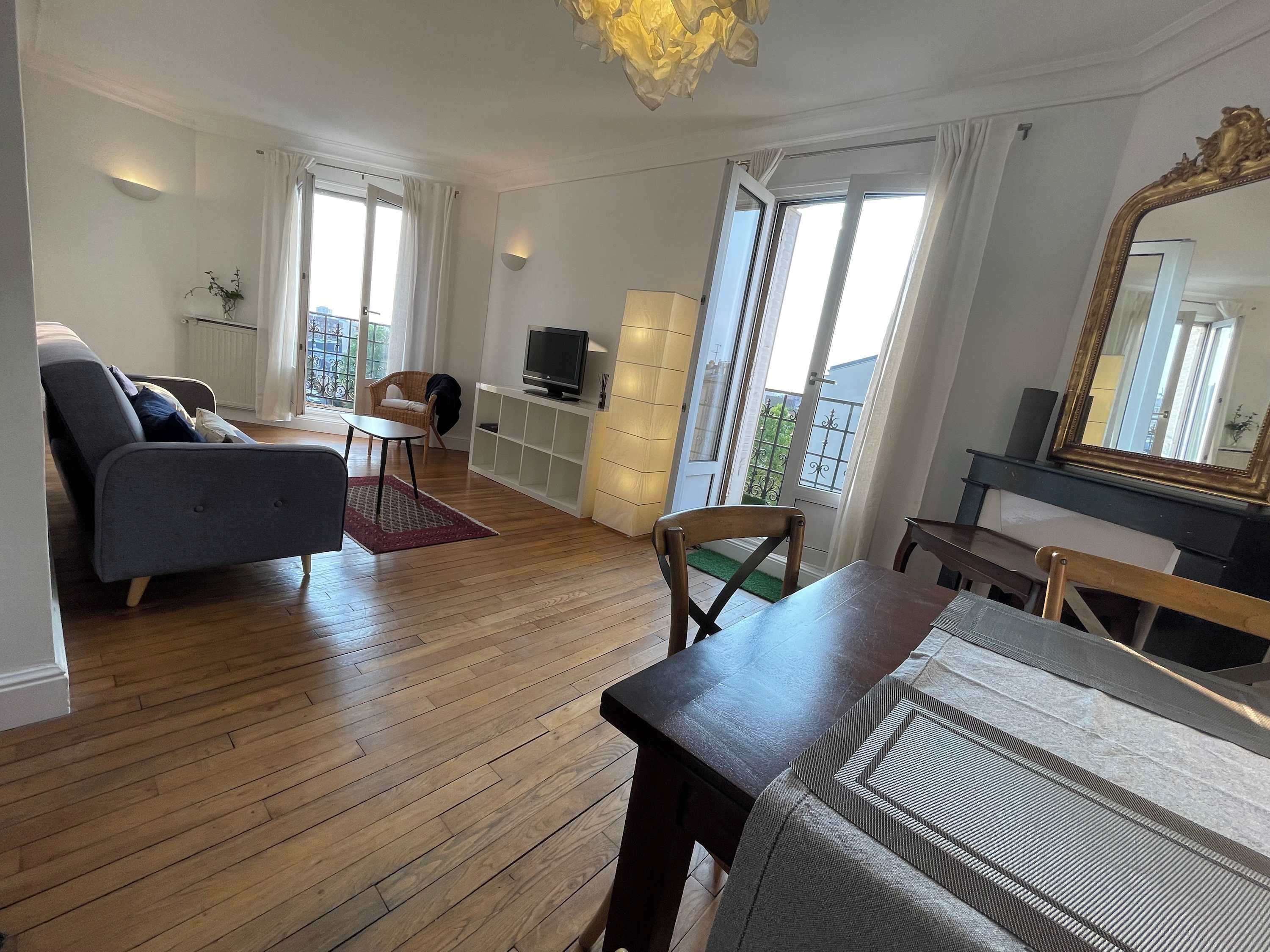 Ein Wohnzimmer mit einer Couch, einem Fernseher, einem Esstisch und einem Klavier.