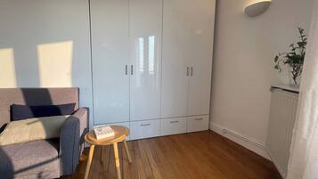 Une pièce avec un canapé gris, une petite table en bois, une armoire blanche et une plante en pot.