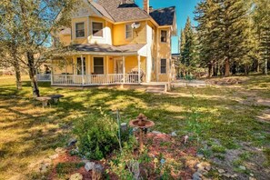 A two-story house with a porch, surrounded by a grassy yard and trees. - Dragonfly Estate - the Main House & Studio (South Fork)